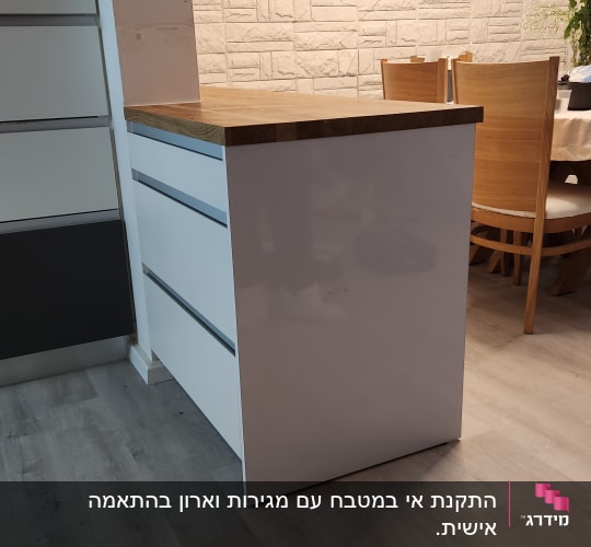 אי מטבח לבן עם משטח עץ, כיסאות עץ ברקע